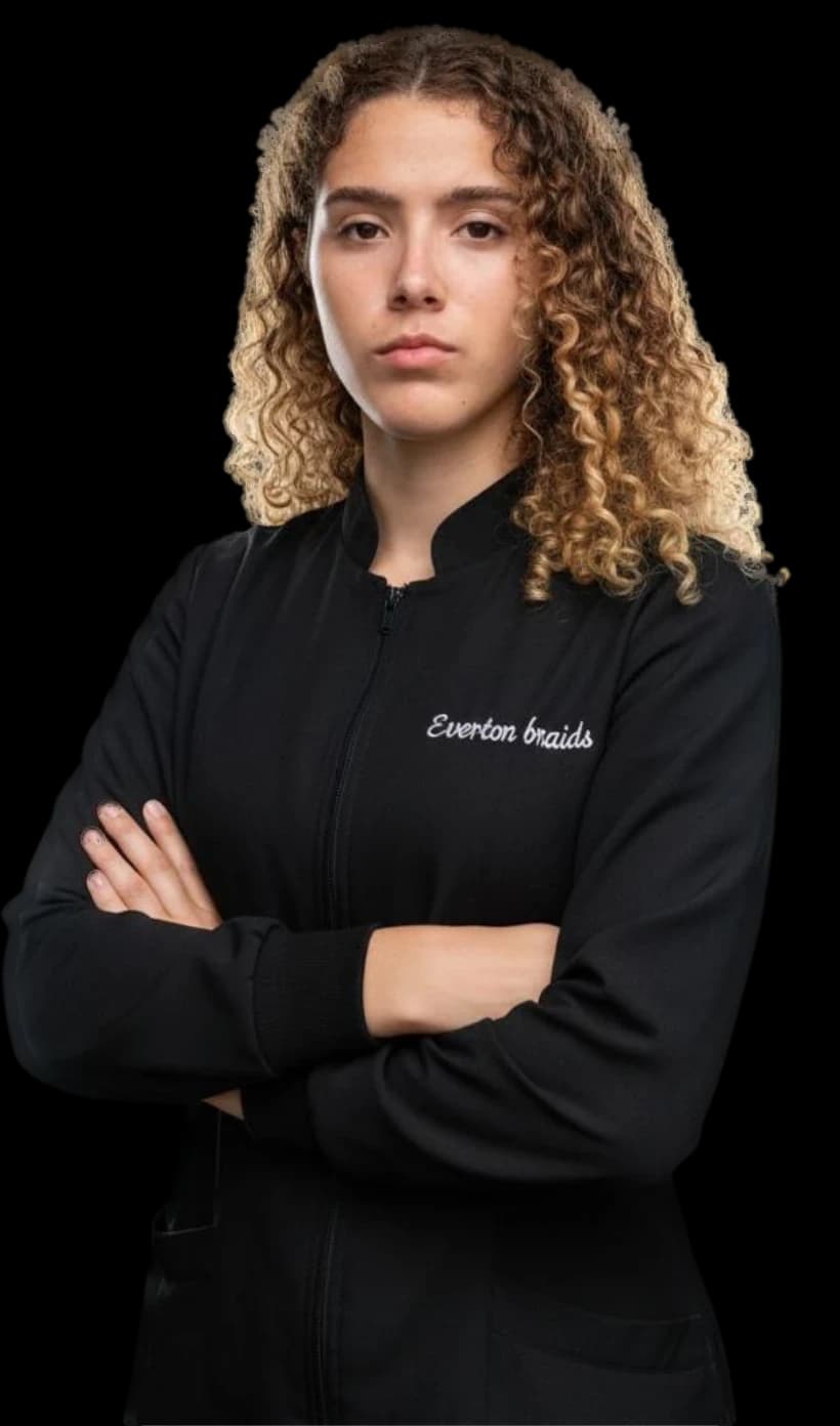 Everton, trancista, de braços cruzados vestindo jaleco preto bordado Everton Braids